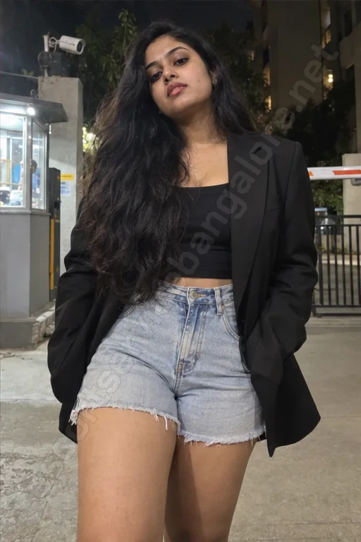 Megha in a black blazer and denim shorts at a Sarjapur Road society gate