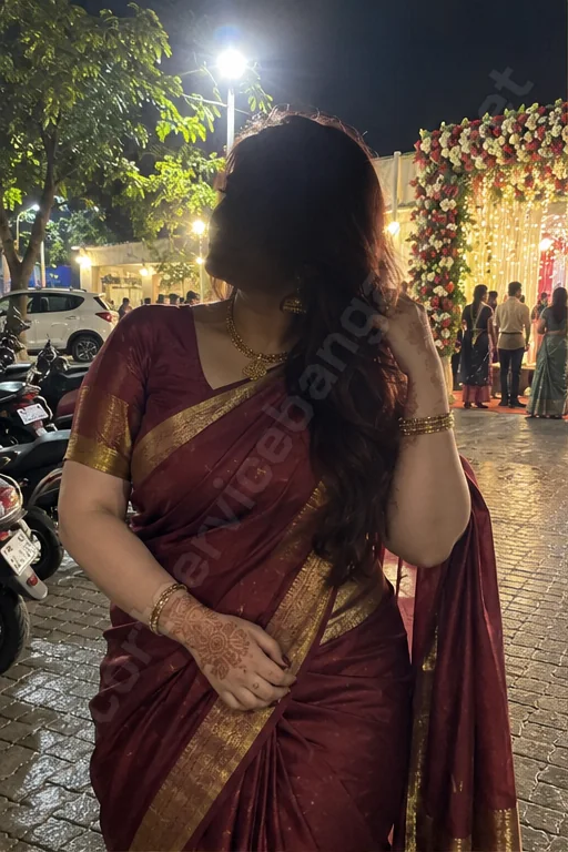 Tamanna in a maroon saree outside a wedding hall at night